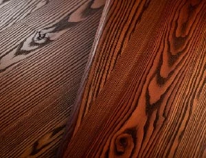 A close-up of polished oak or walnut-wood textures with light highlighting natural grains